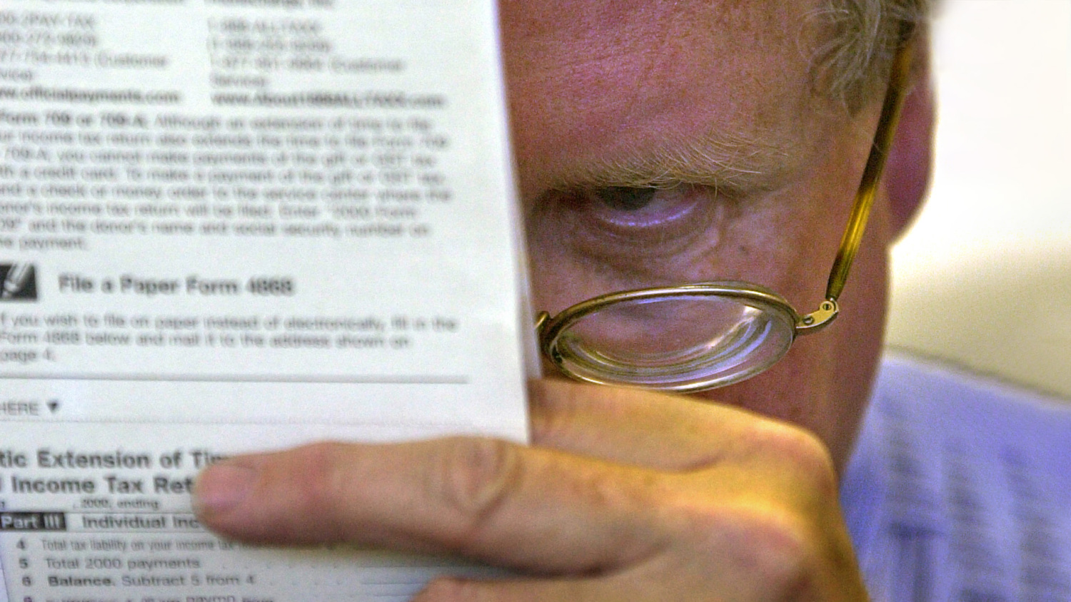 Man with reading glasses looking at government forms