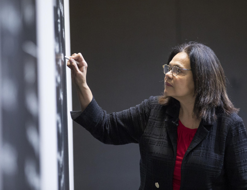Harvard faculty member, Kimberlyn Leary, writes data on a blackboard of a classroom