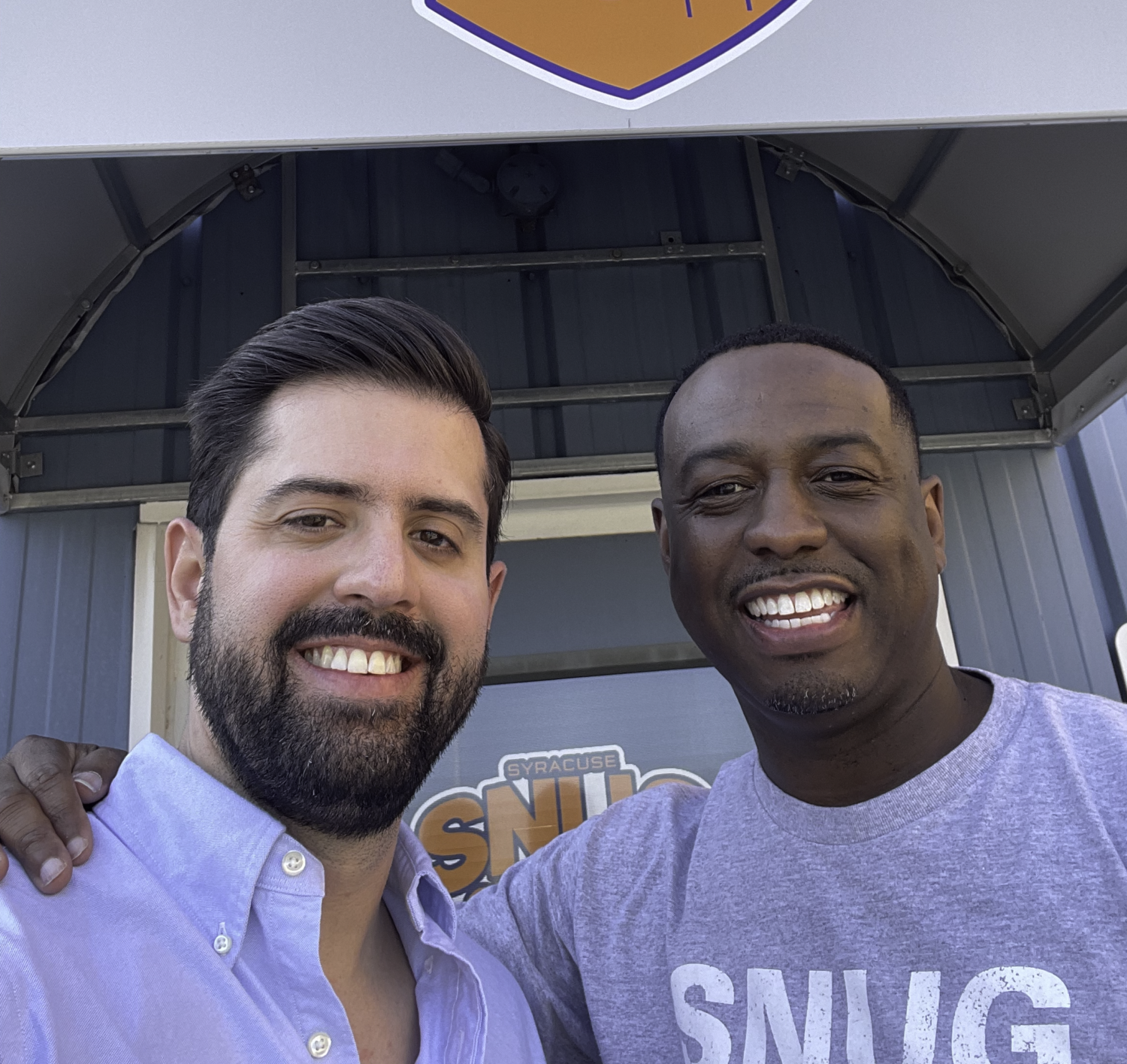 Two men pose in front of a nonprofit office