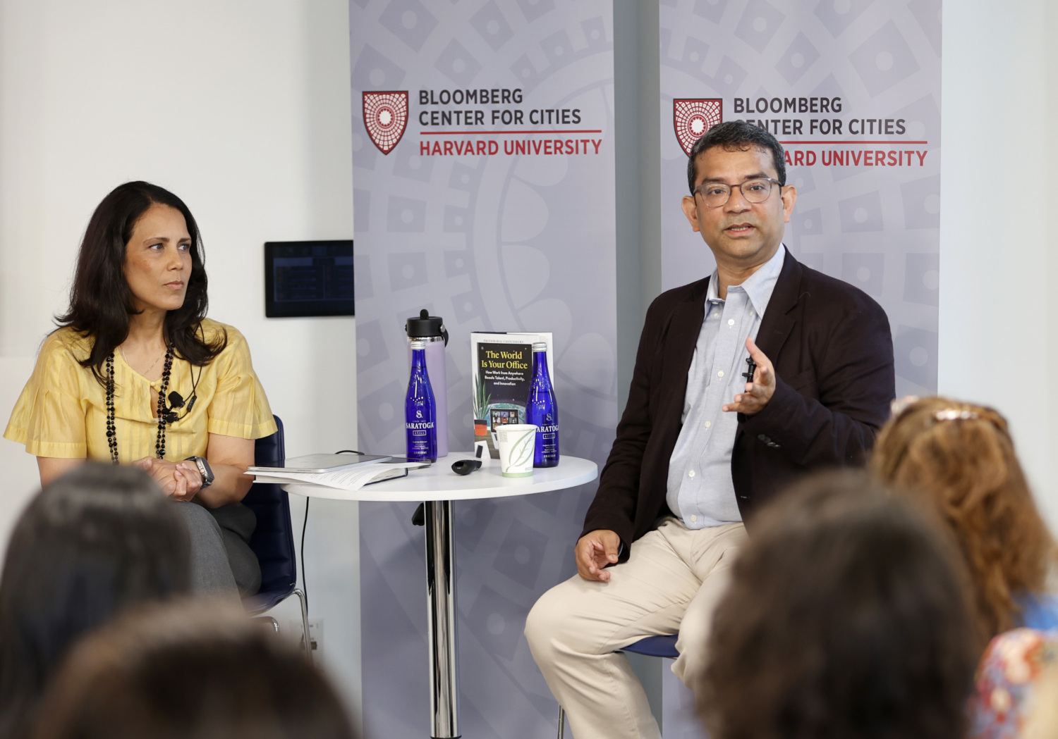 Raj Choudhury sitting on stage across from Michelle De La Isla speaking to the audience